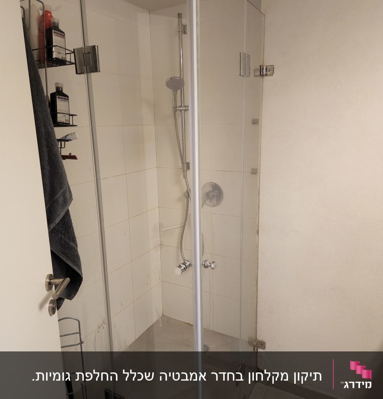 מקלחון זכוכית עם מדף בקבוקים ומגבת תלויה